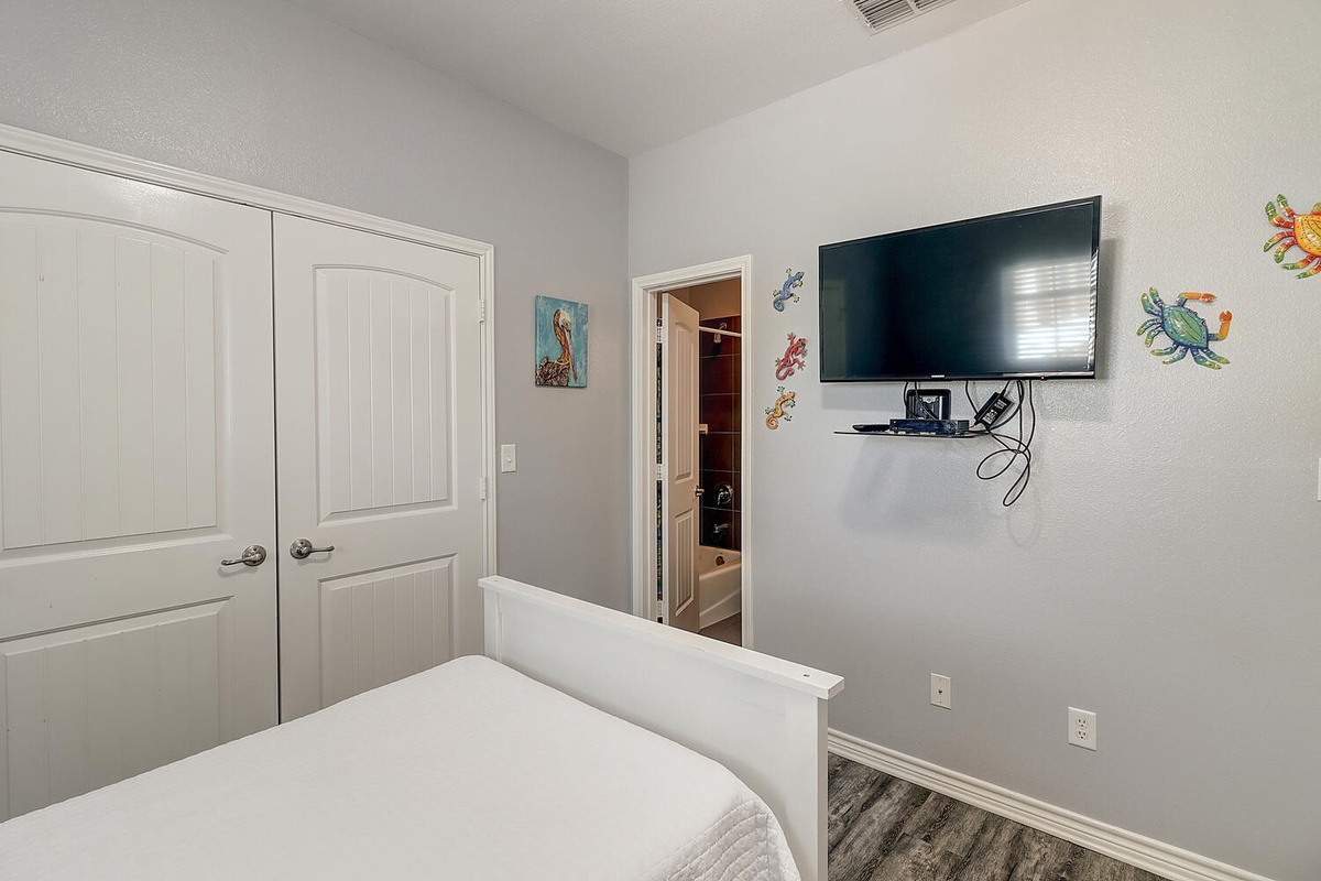 Drift off peacefully in your cozy bedroom, featuring charming coastal decor and a wall-mounted TV for your evening entertainment.