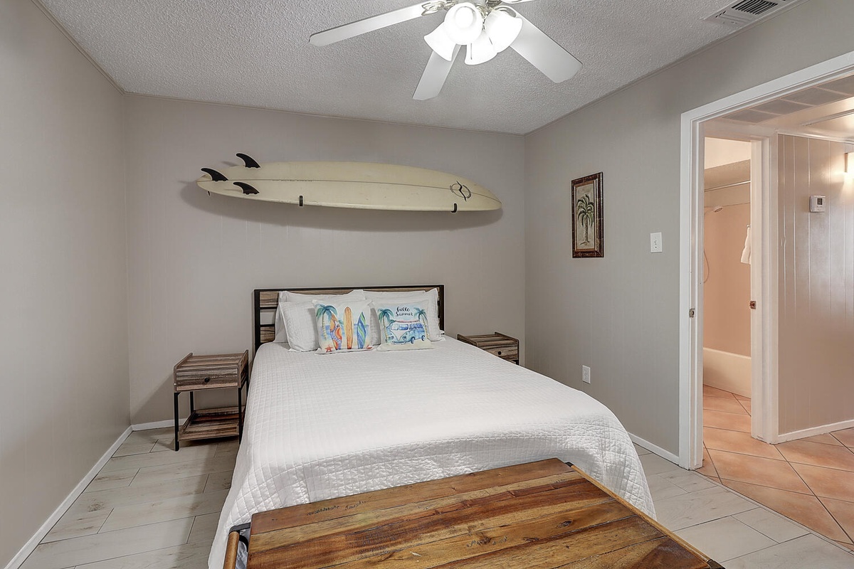Drift off in your coastal bedroom with surfboard art overhead and beach vibes throughout this serene space.