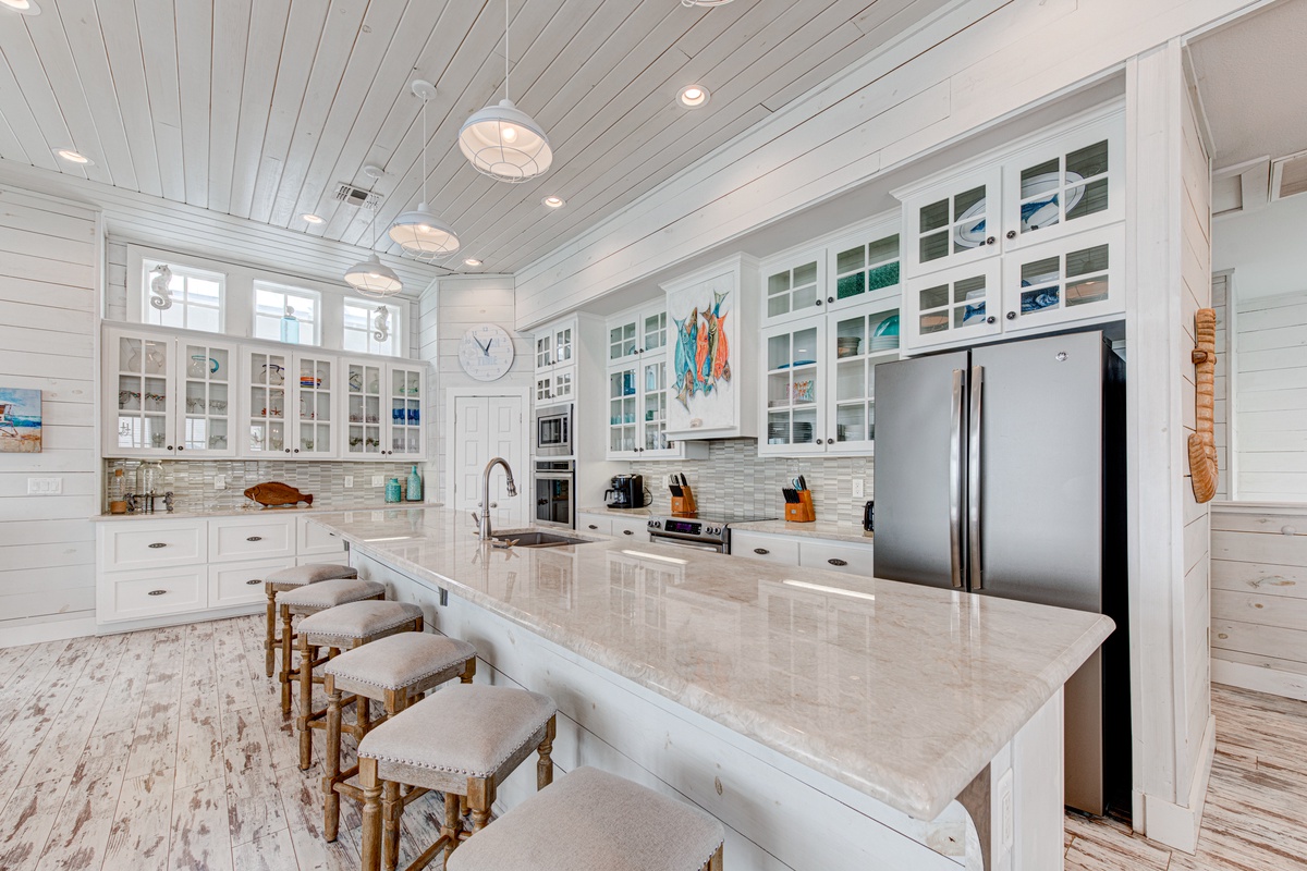 You'll love preparing meals in this stunning coastal kitchen with marble counters, glass cabinets, and stainless appliances.
