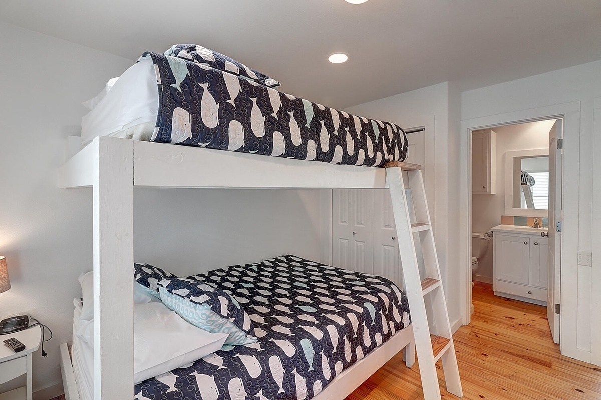 Cozy bunk beds with charming whale bedding create a perfect nautical hideaway for your family's seaside adventure.