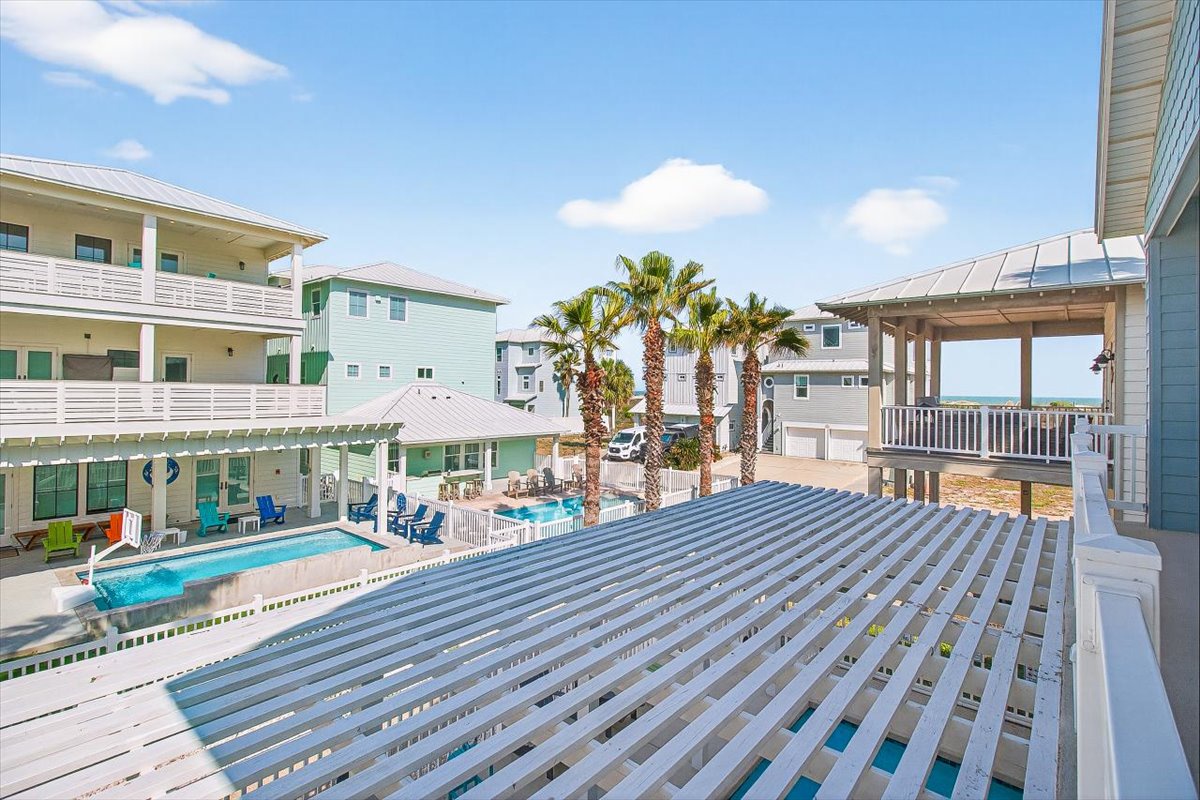Coastal community with colorful beach houses, palm trees, and shared pool area creating a vibrant vacation atmosphere.