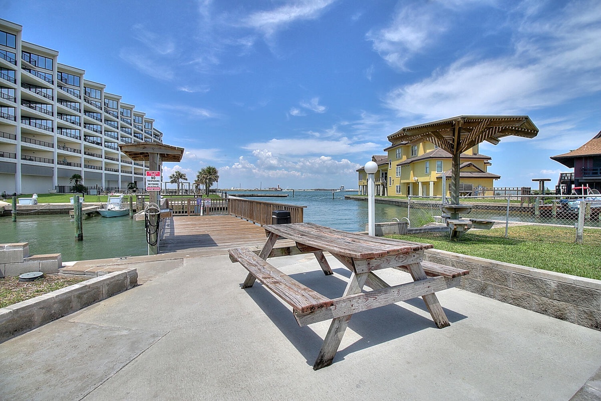 Waterfront picnic area with dock access and bay views surrounded by coastal buildings.