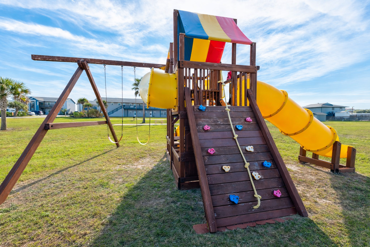 Colorful playground with climbing wall, swings, and yellow slide offers endless fun for your little ones.