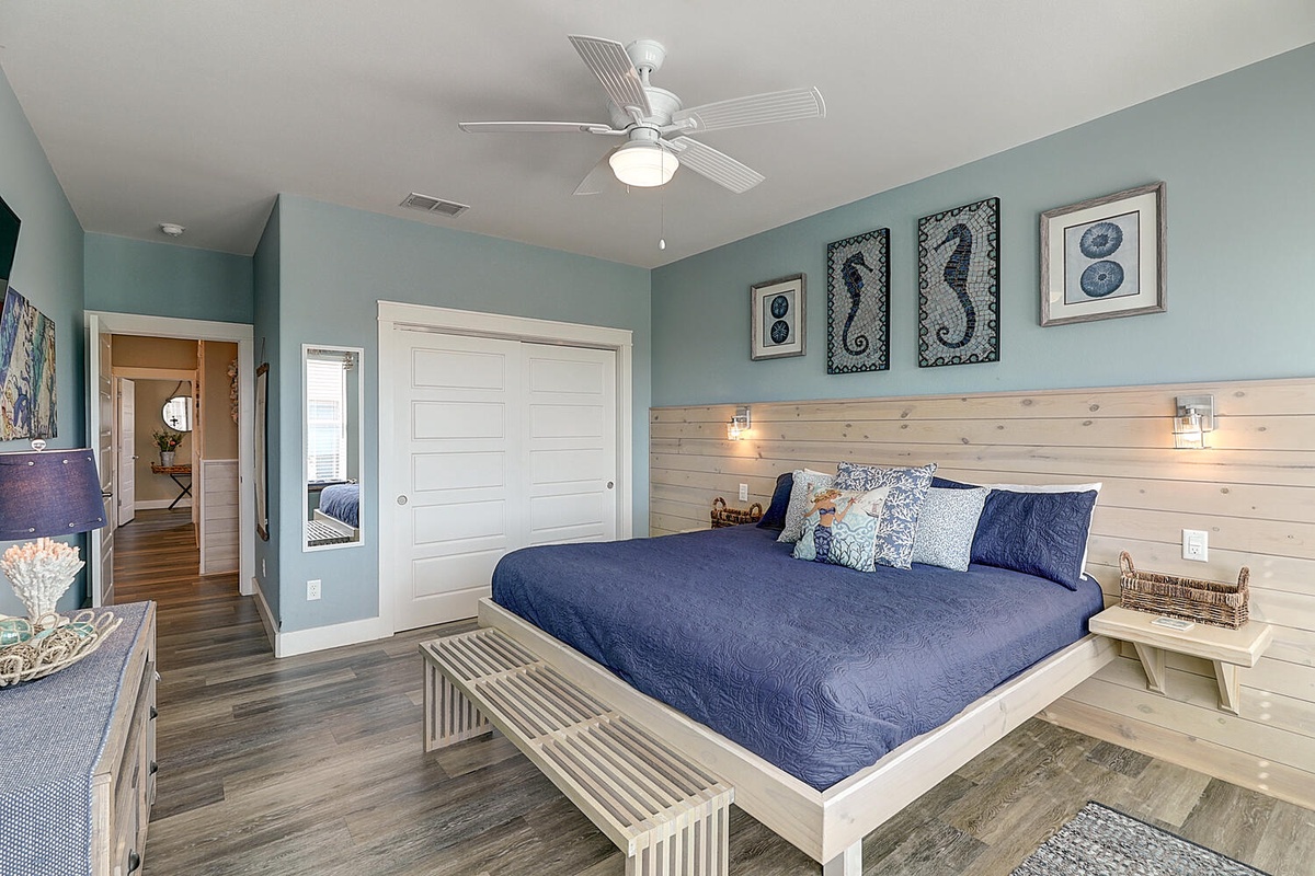 Drift off in coastal comfort with plush navy bedding, gentle ceiling fan breezes, and serene seafoam walls adorned with charming seahorse art.
