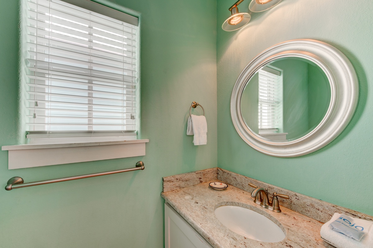 Refresh in your elegant powder room featuring soothing mint walls, granite countertops, and warm brass fixtures that create a spa-like atmosphere.