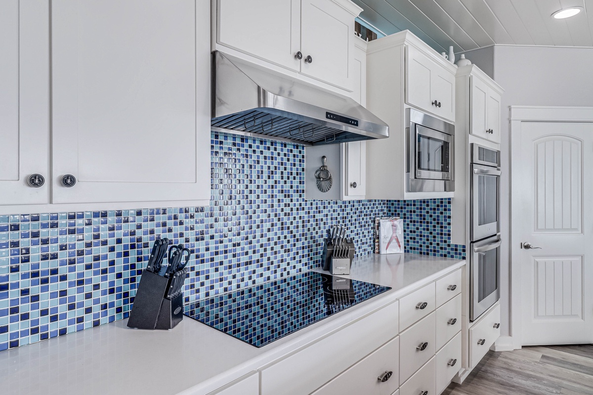Cook your favorite meals in this fully equipped kitchen with beautiful blue mosaic backsplash and modern appliances.
