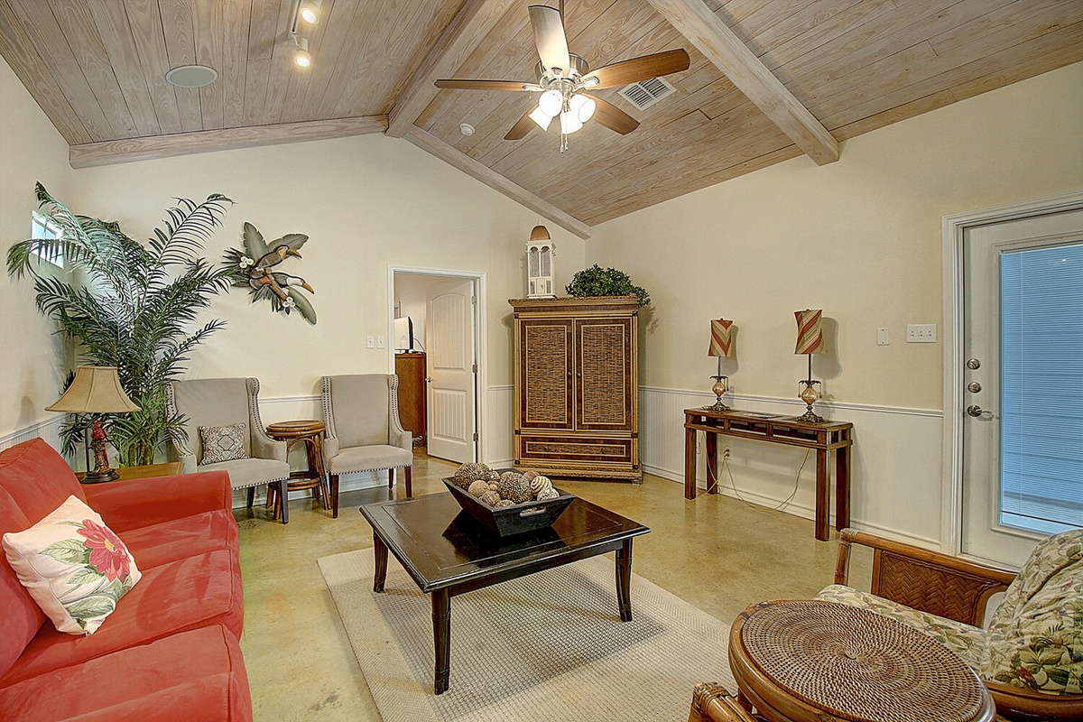 Relax in your tropical-inspired living room with vaulted wood ceilings, comfortable seating, and charming coastal decor.