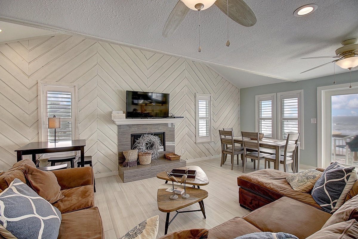 Unwind in your stylish living space featuring plush seating, warm fireplace, and stunning chevron accent wall that creates the perfect coastal retreat.