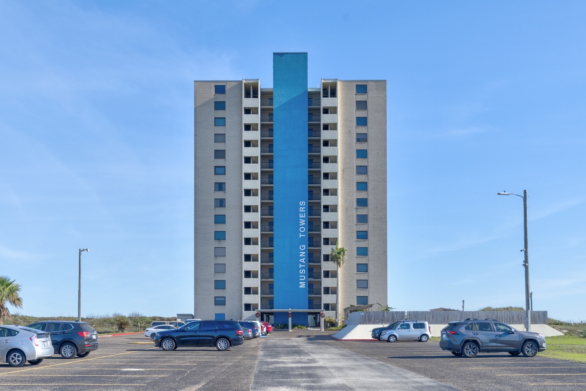 Modern high-rise property with convenient parking and striking blue accent tower under clear coastal skies.
