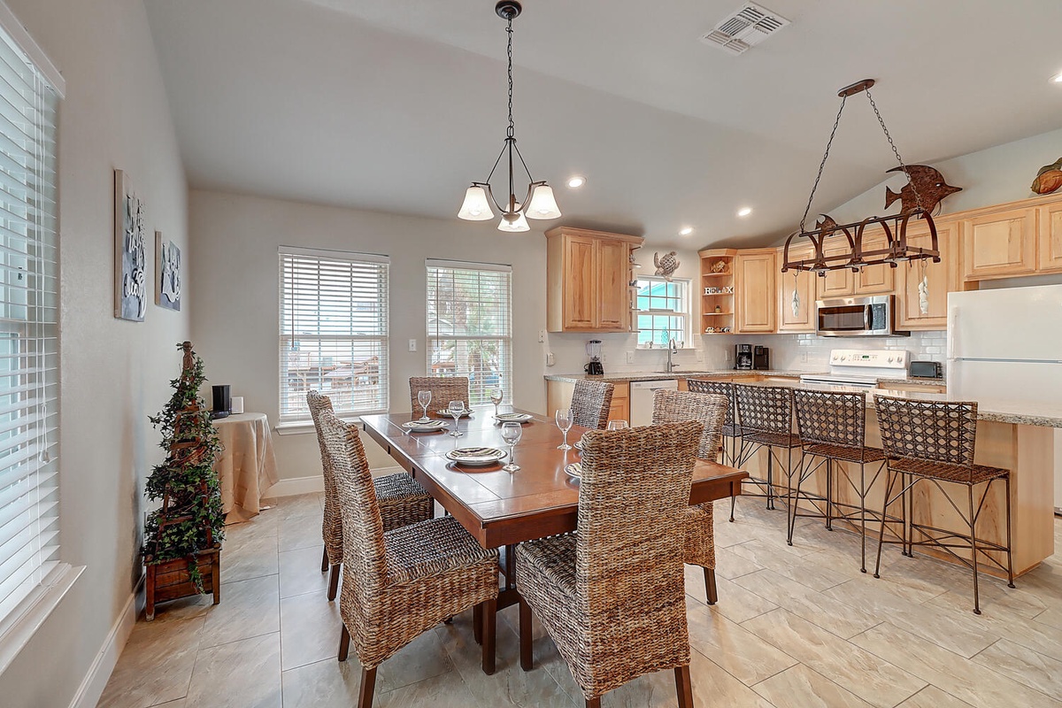Gather around your open-concept kitchen and dining space, where warm wood cabinetry and wicker seating create the perfect setting for shared meals and conversations.