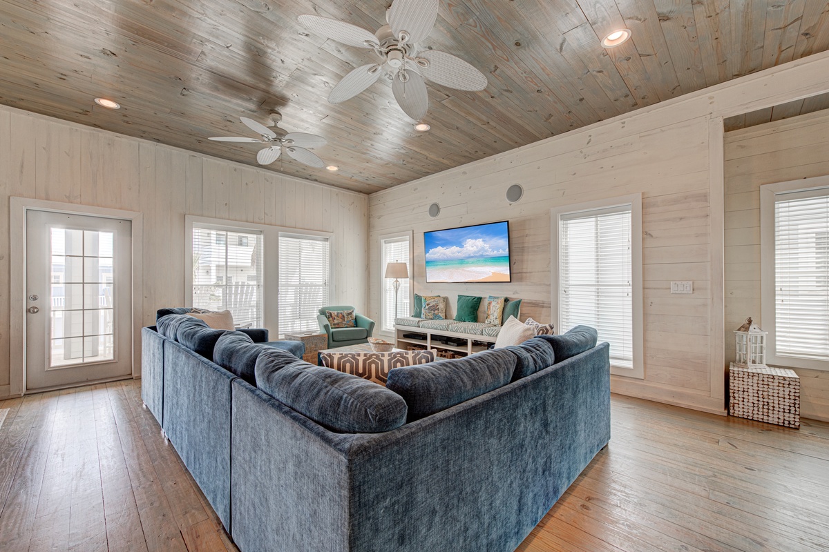 Sink into the plush sectional and watch your favorite shows on the large TV in this bright, airy living room with stunning wood-beam ceilings.