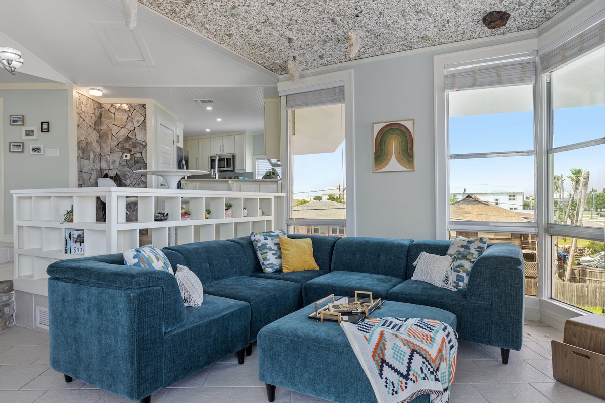 Relax in your stylish living room with plush sectional seating and colorful art, while enjoying views through floor-to-ceiling windows.