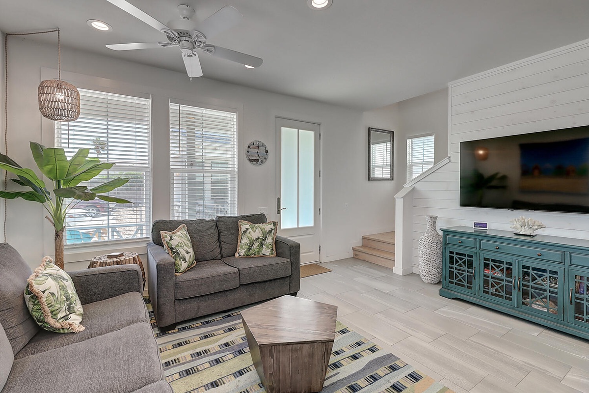 Relax in your bright, modern living room with plush seating, tropical touches, and entertainment center for cozy evenings.