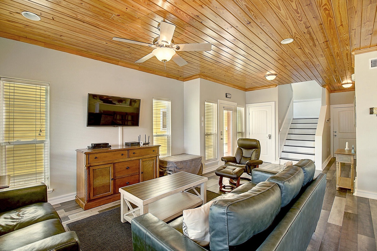 Unwind in your spacious living room with stunning wood ceiling, plush leather seating, and entertainment center for perfect relaxation.