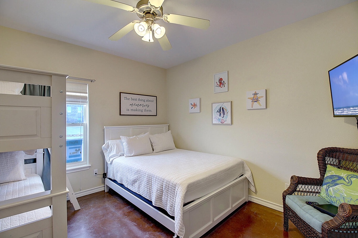 Your coastal-themed bedroom offers crisp white linens, charming nautical artwork, and a ceiling fan for comfort during your stay.