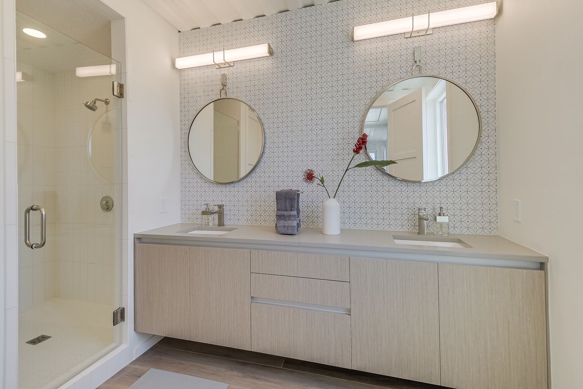 Pamper yourself in this stunning modern bathroom featuring dual vanities, elegant mirrors, and a spacious glass shower.