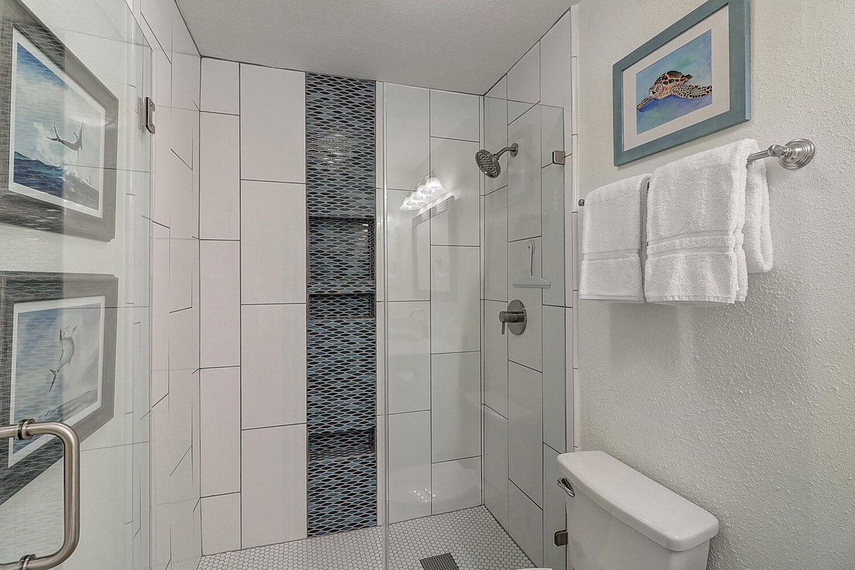 Step into your spa-like bathroom featuring a stunning glass-enclosed shower with elegant tile work and fresh towels awaiting you.