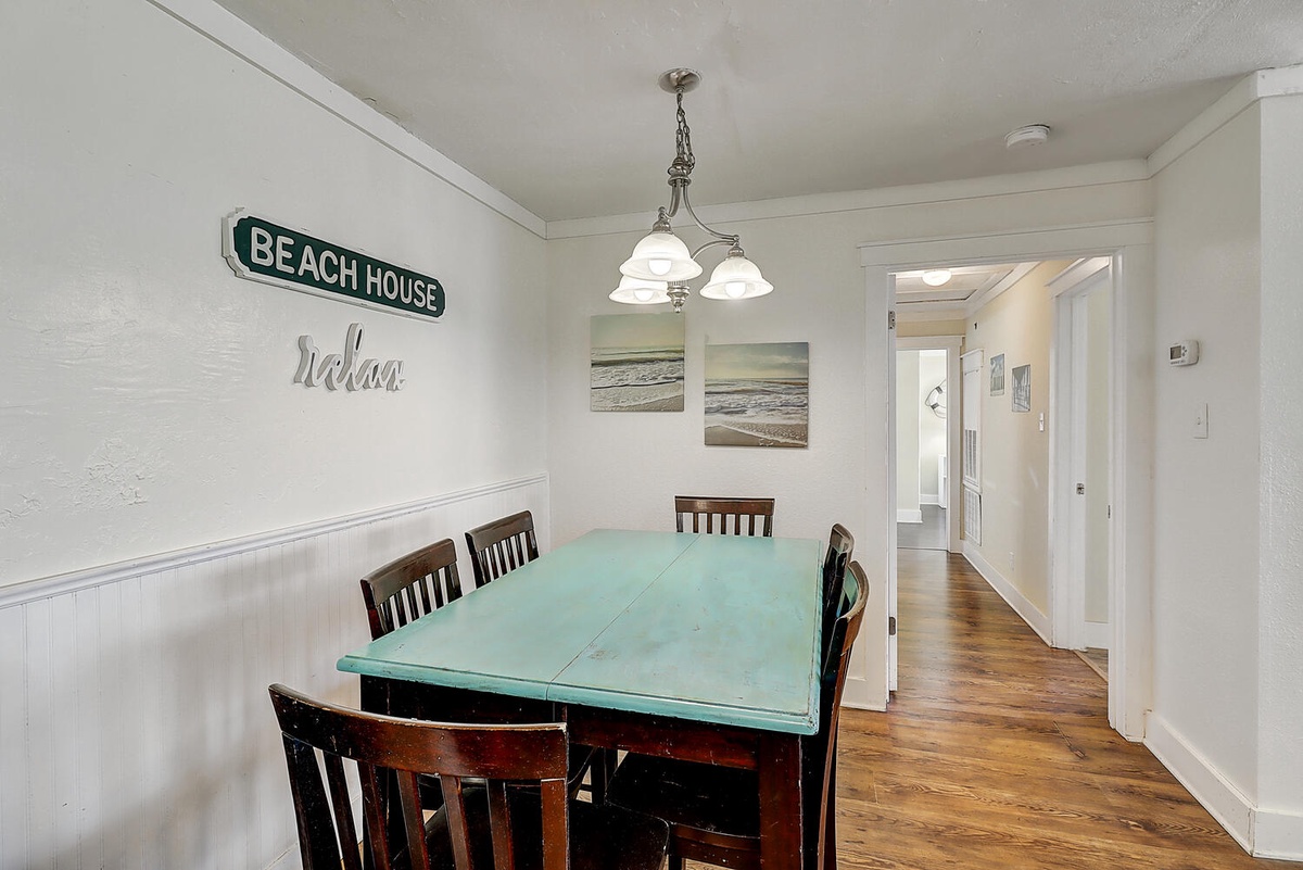 Your coastal dining space invites relaxed meals with charming beach artwork and warm wooden floors that flow throughout your home.