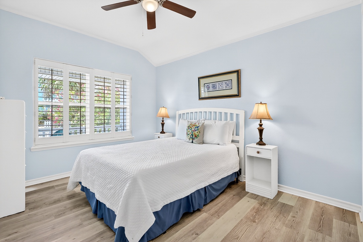 Drift off in your peaceful blue bedroom with soft lighting and tropical garden views through plantation shutters.