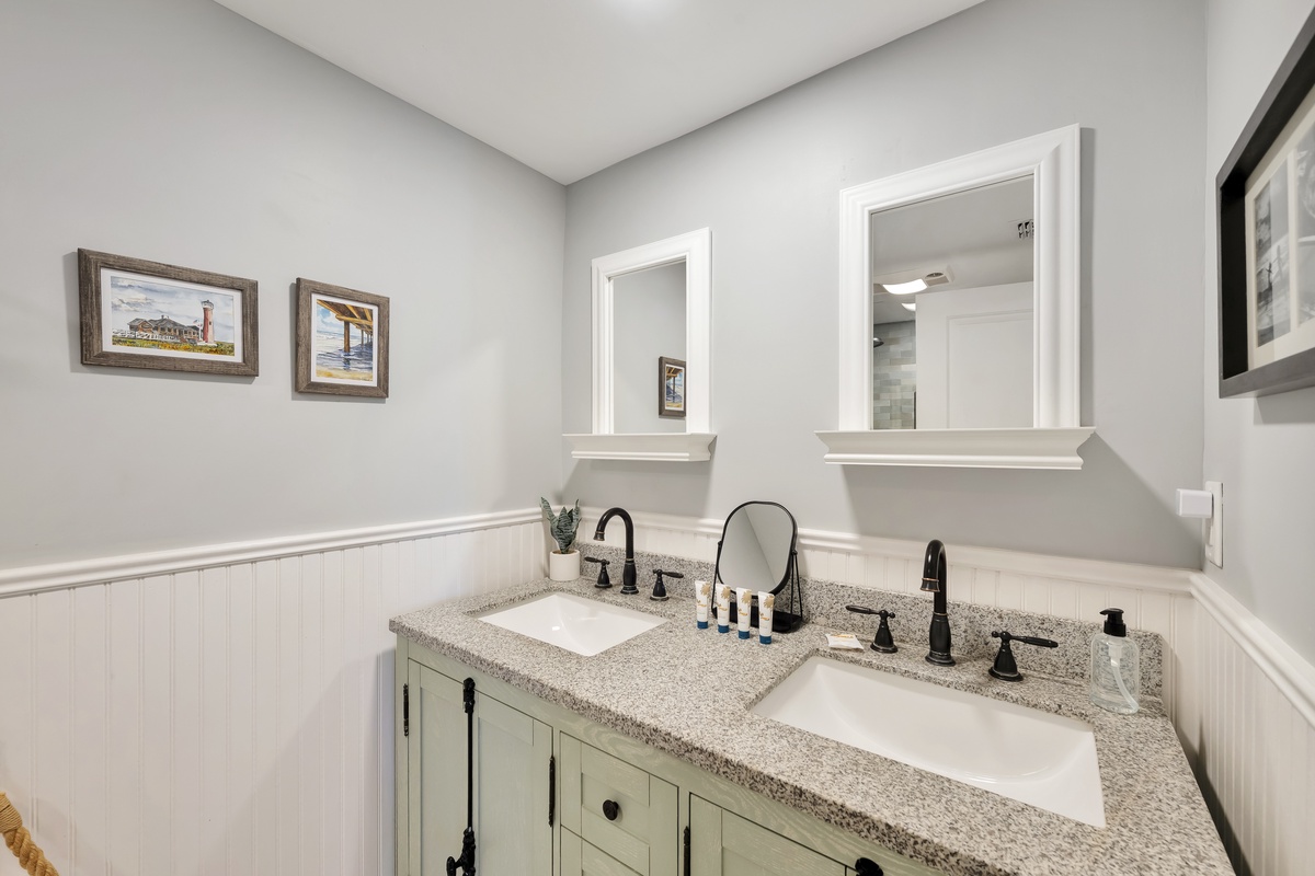 Step into your private double-vanity bathroom, where granite countertops and charming coastal artwork create an elegant morning routine.