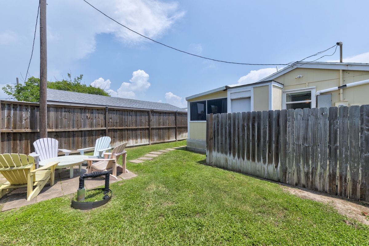 Your private backyard retreat awaits with colorful Adirondack chairs on a stone patio, perfect for morning coffee or evening conversations under open skies.