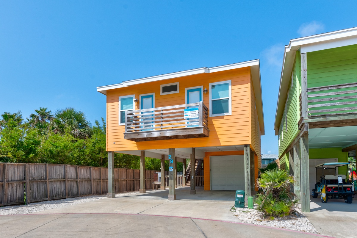 Bright coastal home features elevated design with modern balcony and covered parking in tropical setting.