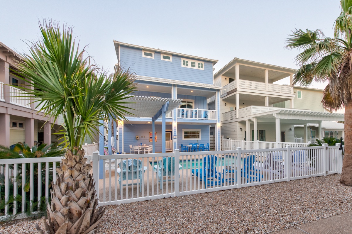 Charming coastal vacation rental featuring multiple levels, balconies, and tropical landscaping in a peaceful beachside neighborhood.