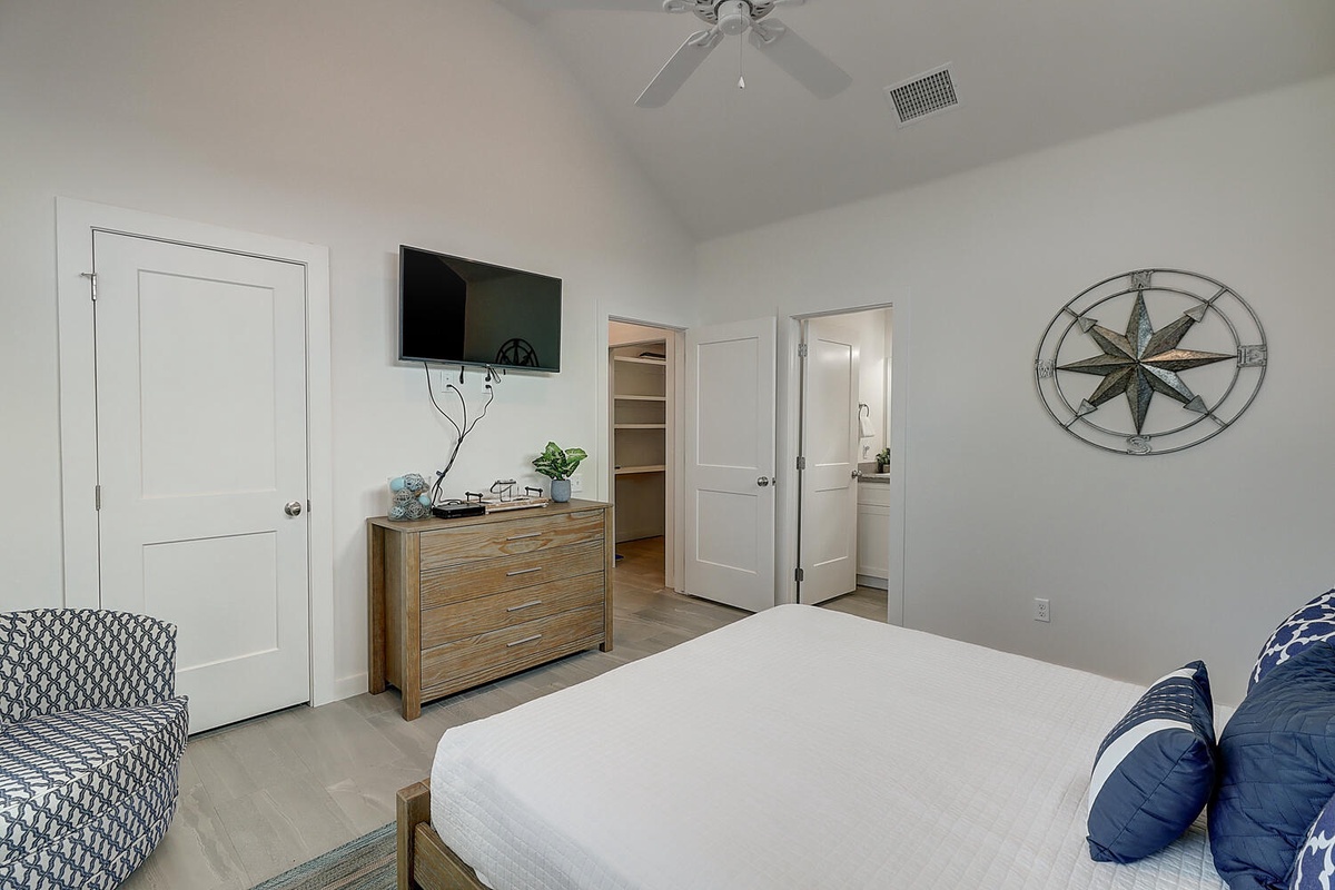 Your bright bedroom features a comfortable bed, smart TV, and stylish compass wall art—perfect for peaceful nights.