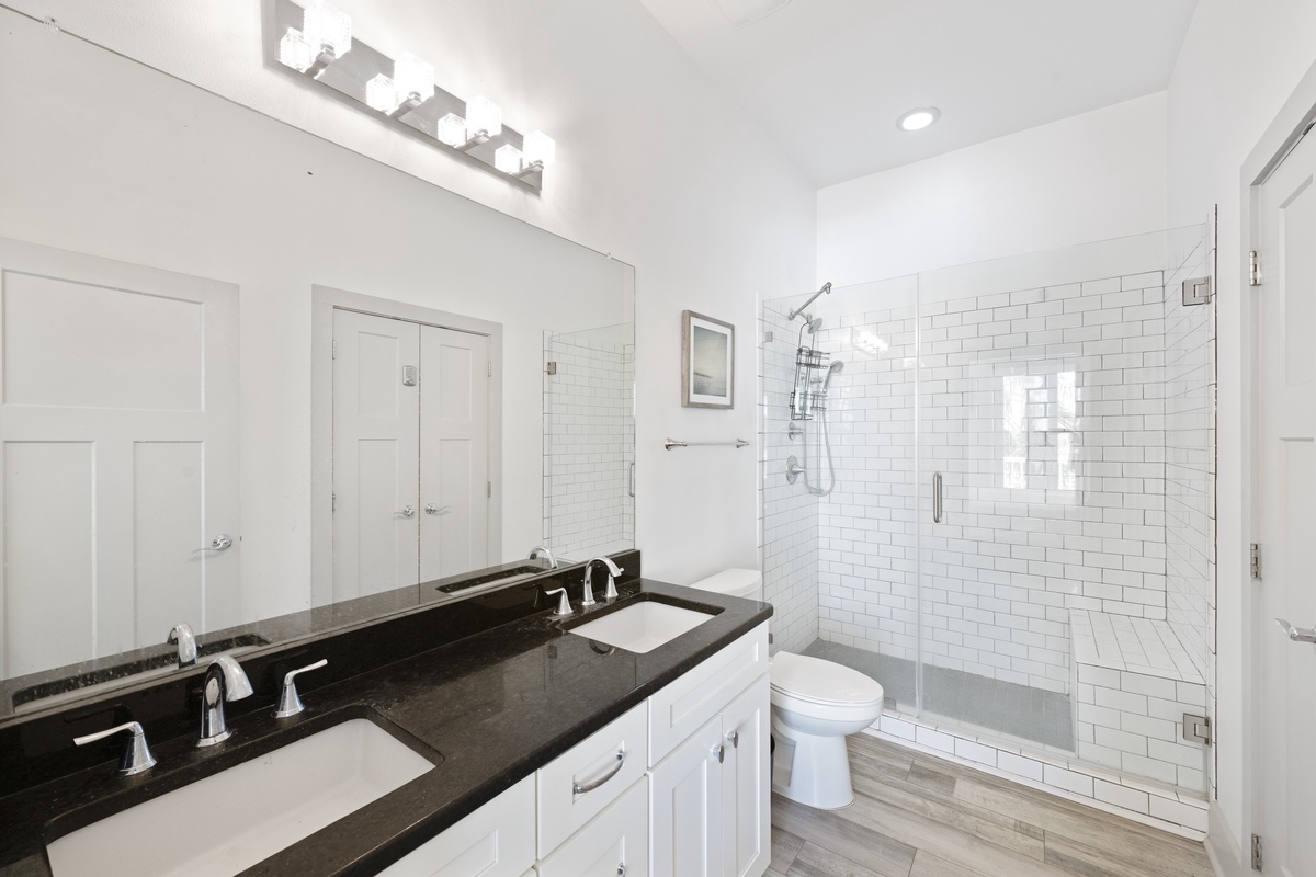 Pamper yourself in this spa-like bathroom with dual vanities, rainfall shower, and elegant subway tile—your perfect retreat.