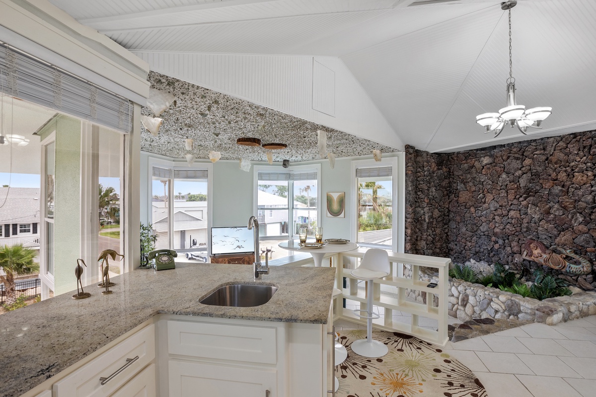 Your open kitchen flows into an elegant dining space where granite meets stone accent walls, creating a perfect gathering spot.