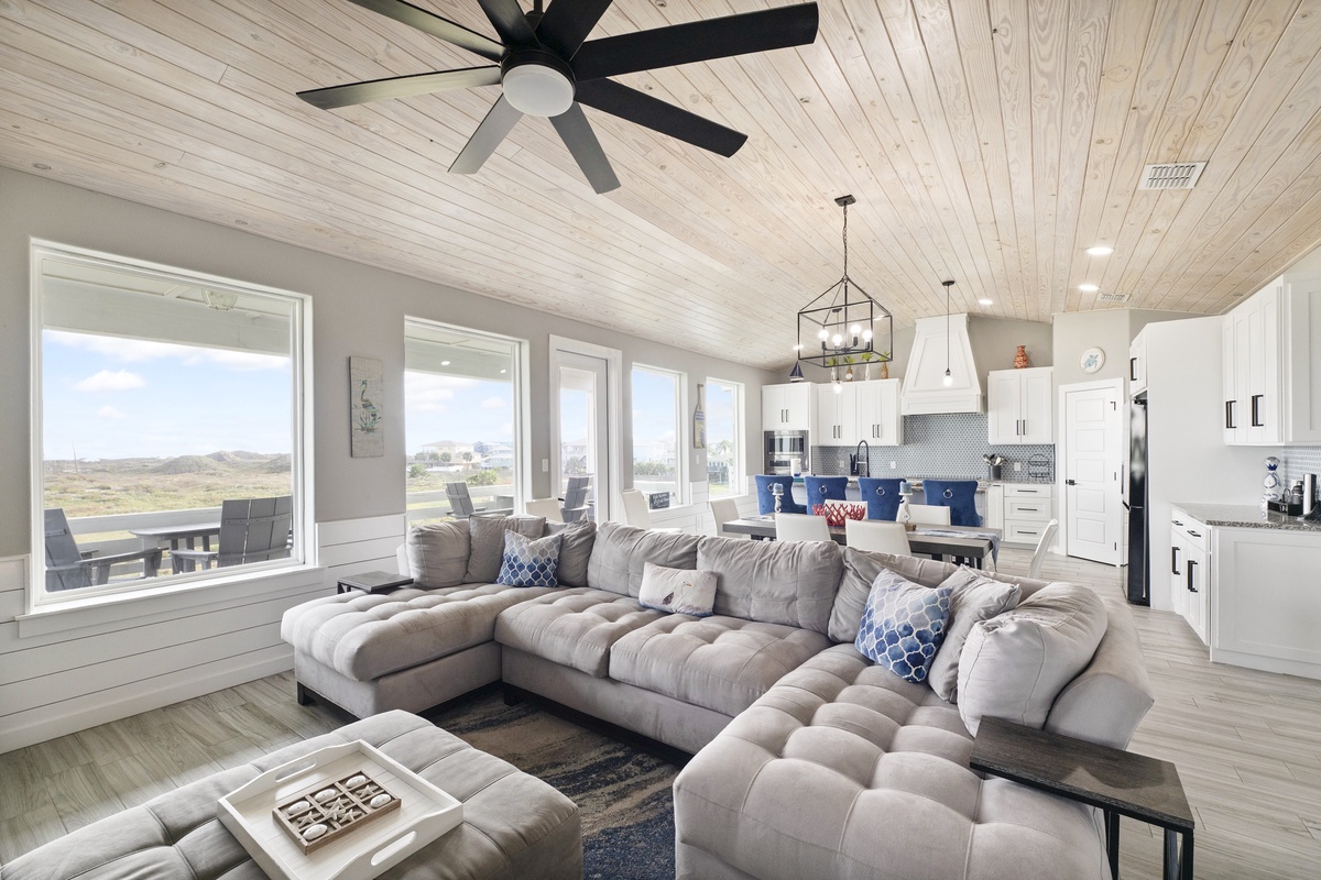Sink into plush sectional seating as natural light floods your open living space, where rustic wood ceilings meet modern comfort.