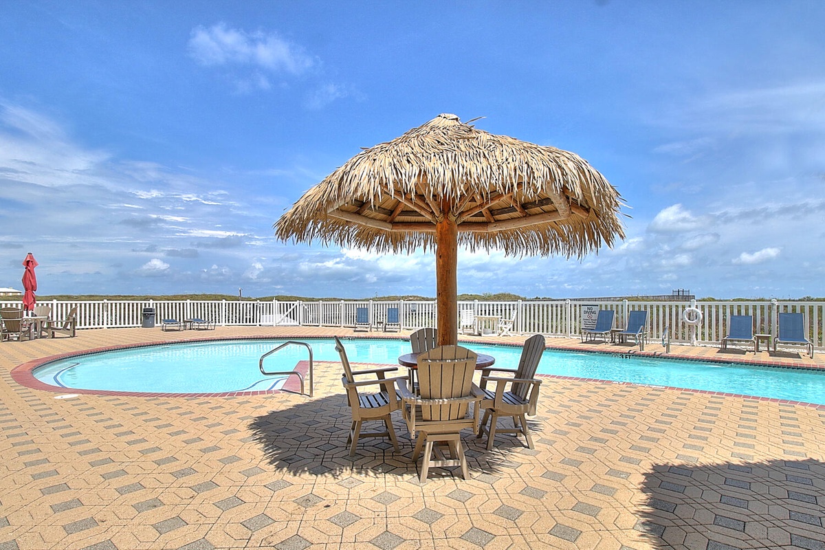 Tropical paradise awaits with thatched umbrellas, crystal-blue pool, and ocean views creating your perfect poolside retreat.