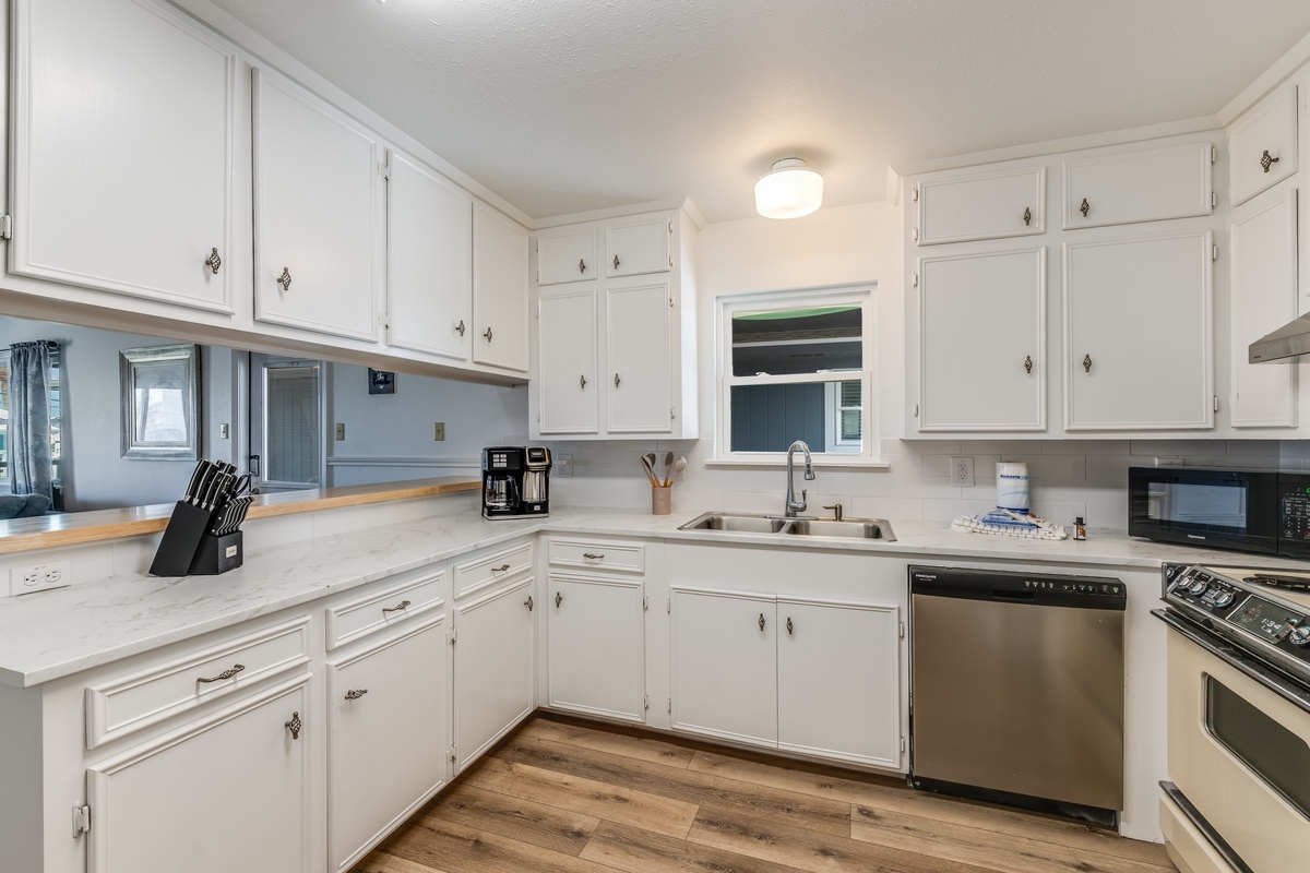 Your fully equipped kitchen invites culinary adventures with crisp white cabinets, modern appliances, and plenty of counter space for meal prep.