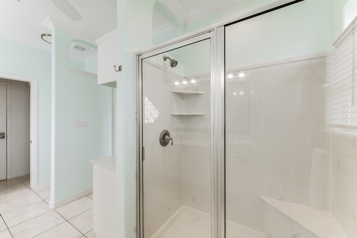 Step into your pristine glass-enclosed shower with built-in shelving and premium fixtures for a refreshing start to your day.