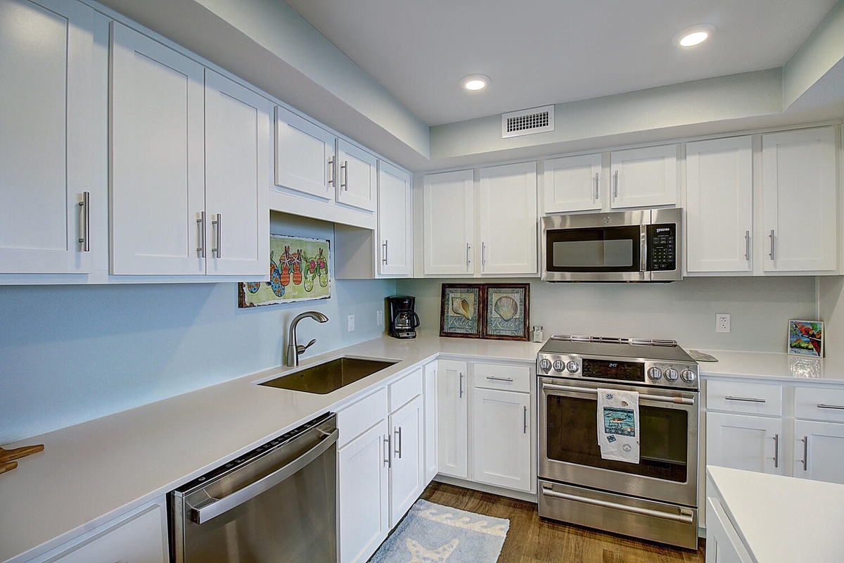 Your fully equipped kitchen features modern stainless steel appliances, crisp white cabinets, and stylish blue backsplash for memorable meal prep.