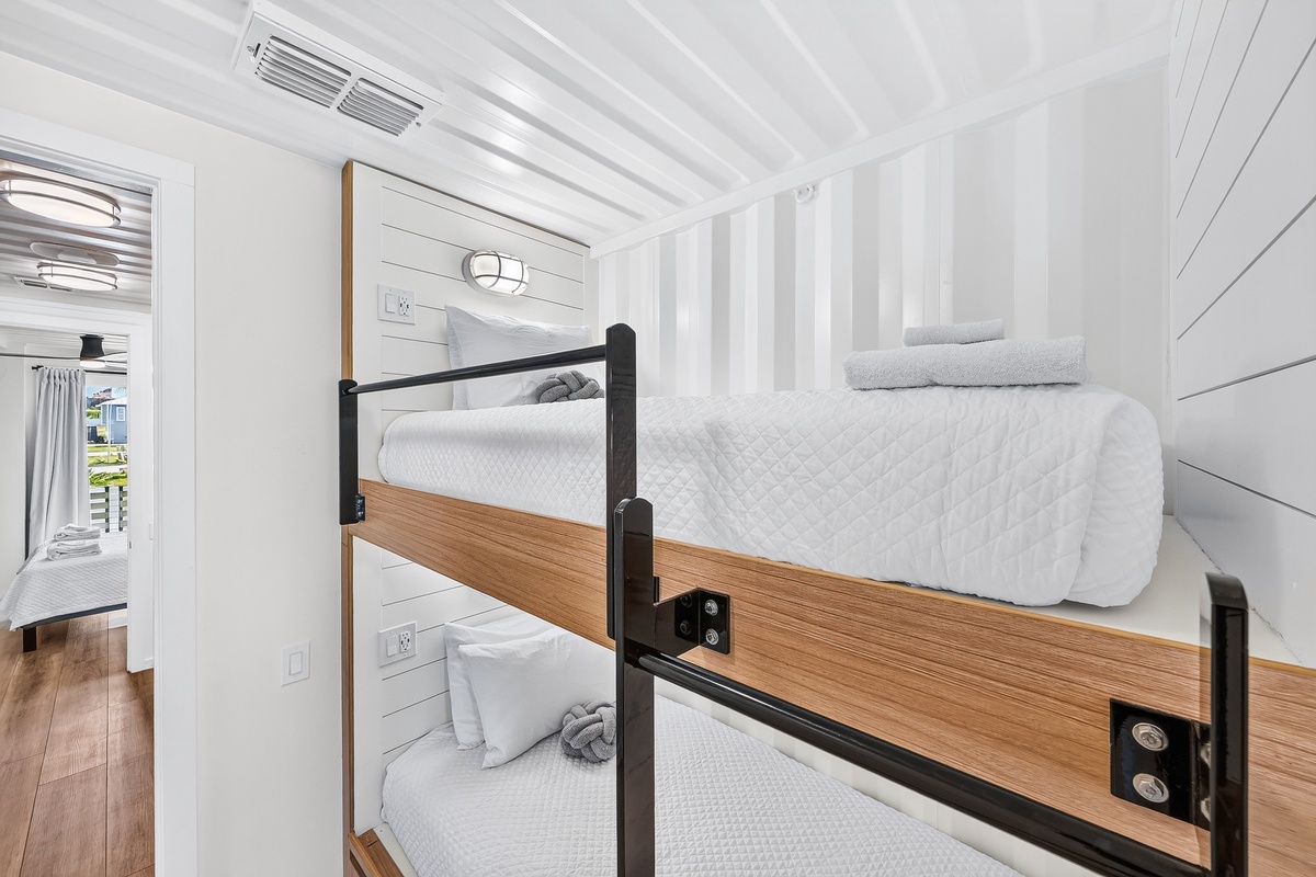 Cozy twin bunk beds with crisp linens await your crew in this charming space. Natural wood accents and a soft coastal feel create the perfect retreat for a restful night.