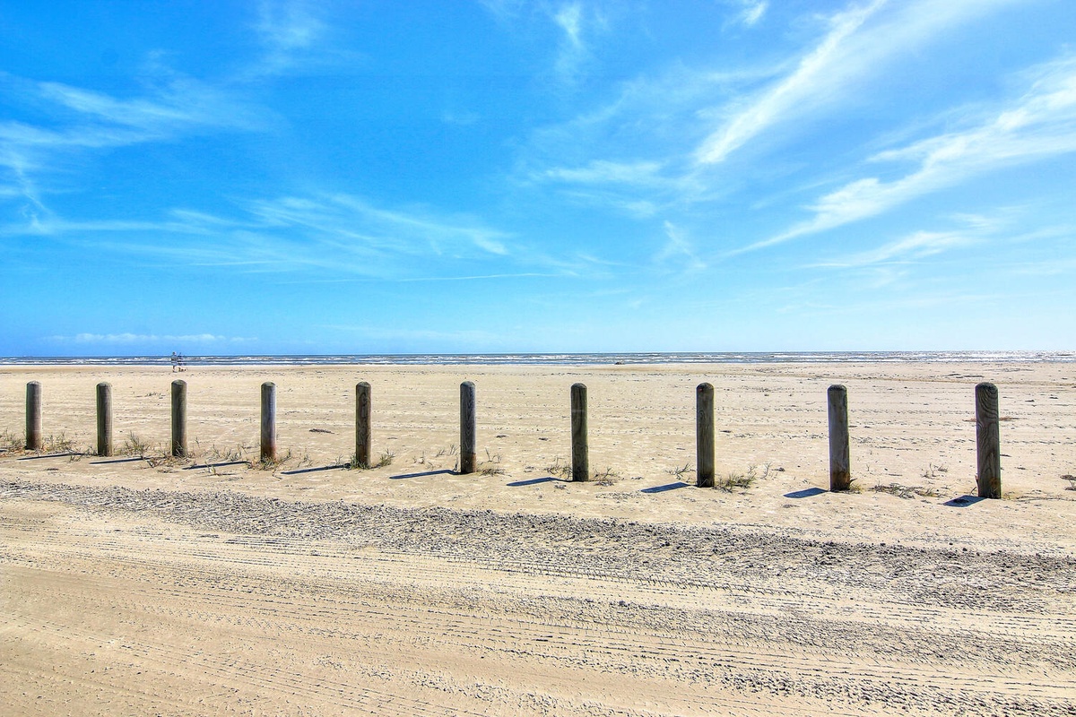 Expansive sandy beach stretches endlessly under brilliant blue skies, offering pristine coastal beauty in the surrounding area.