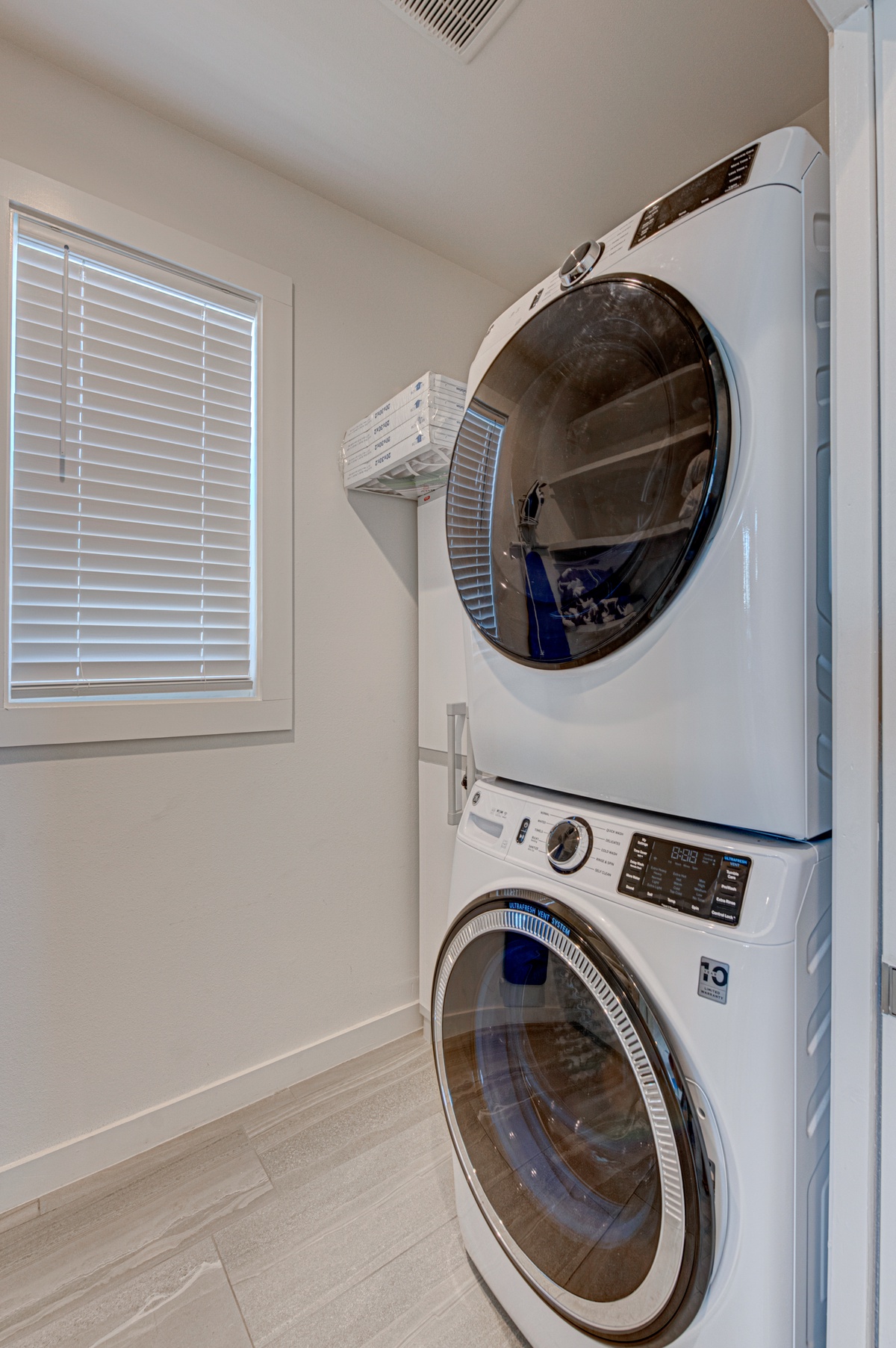 Your private laundry room features modern, full-size appliances in a bright, clean space with natural light streaming through the blinds.