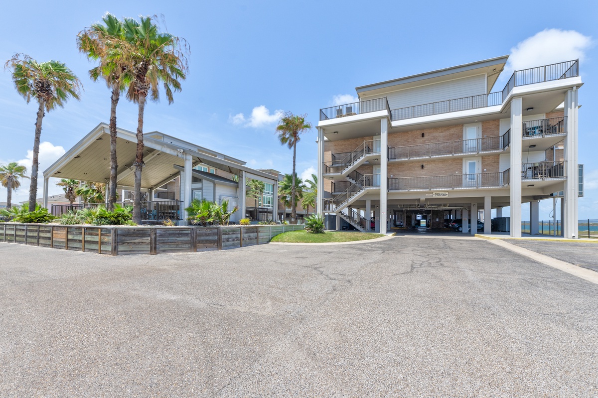 Modern waterfront property with tropical landscaping and convenient ground-level parking for easy arrival.