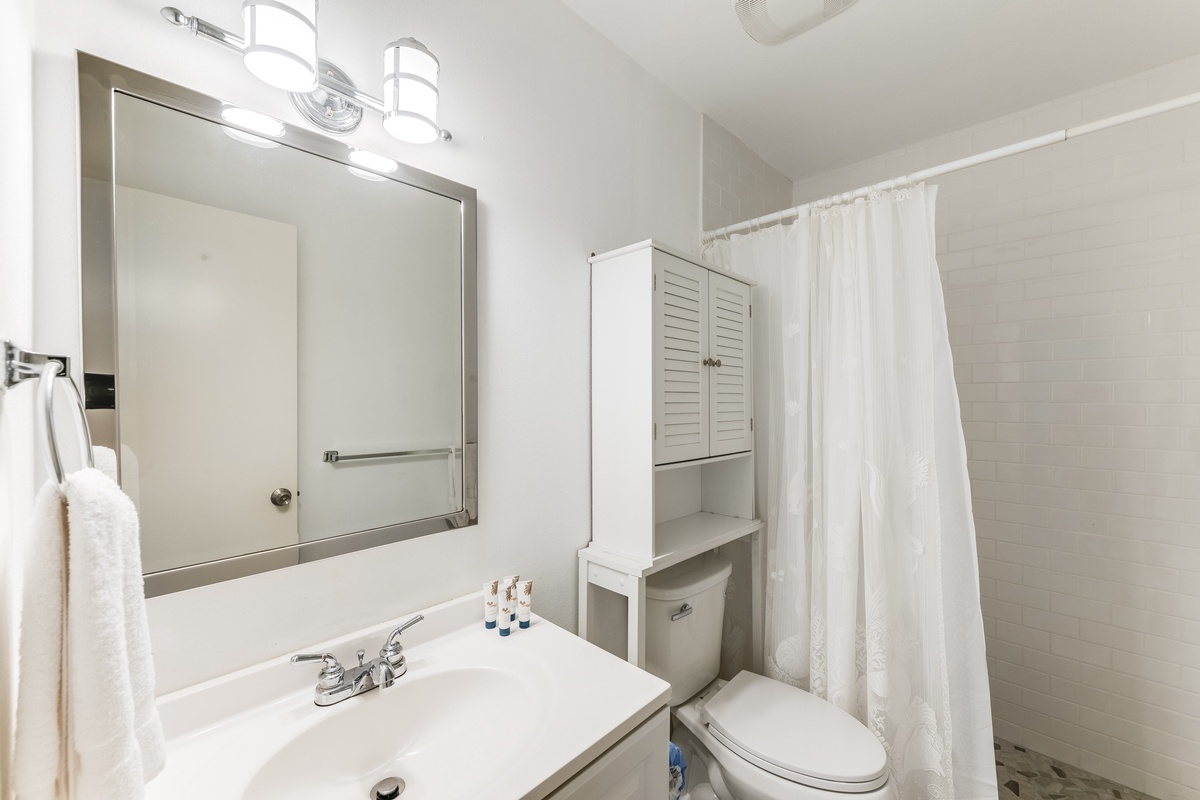 Your private bathroom features a walk-in shower, bright vanity lighting, and freshly laundered towels ready for your arrival.