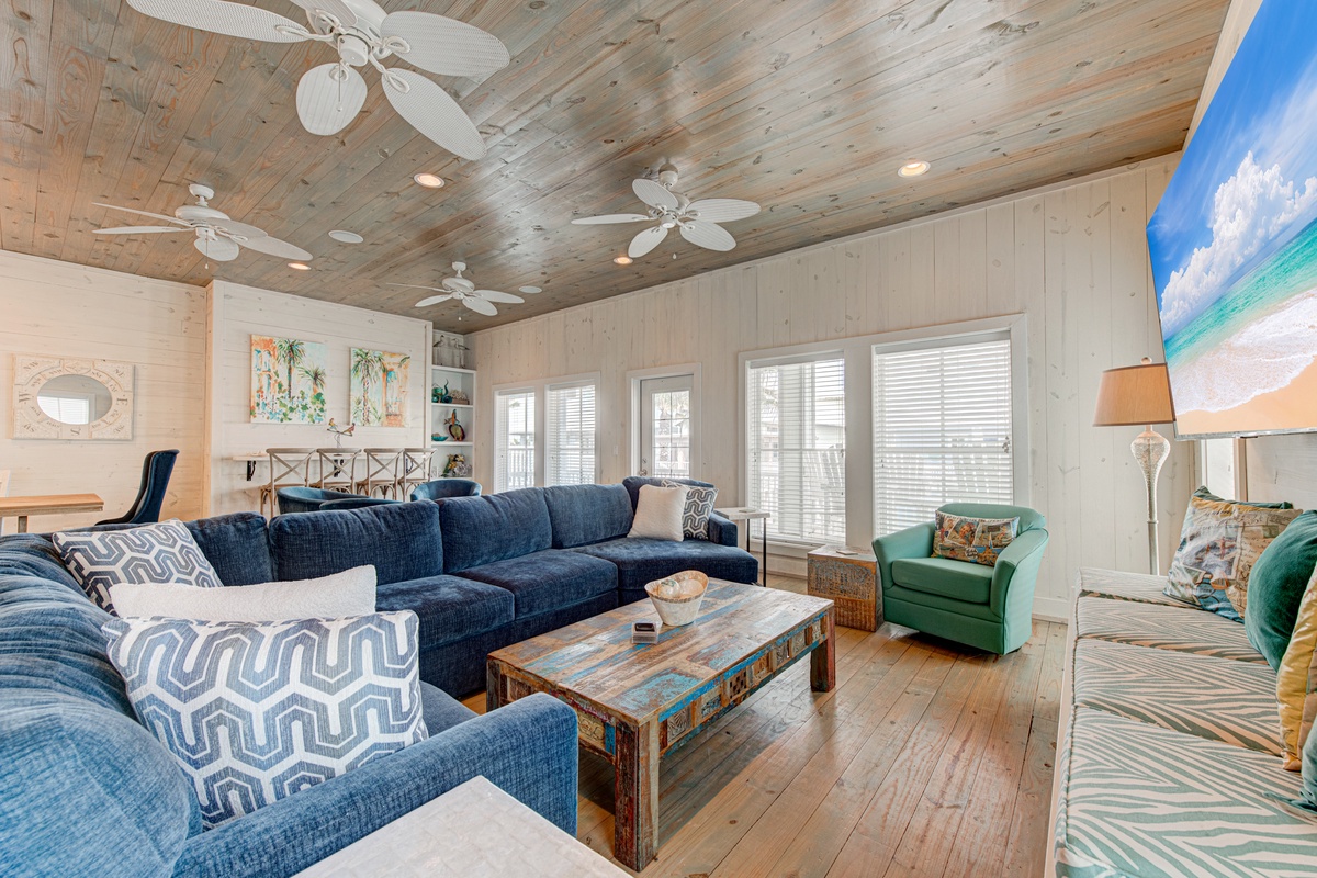 Sink into this spacious living room where coastal charm meets comfort. Ceiling fans keep you cool while you relax on plush seating.