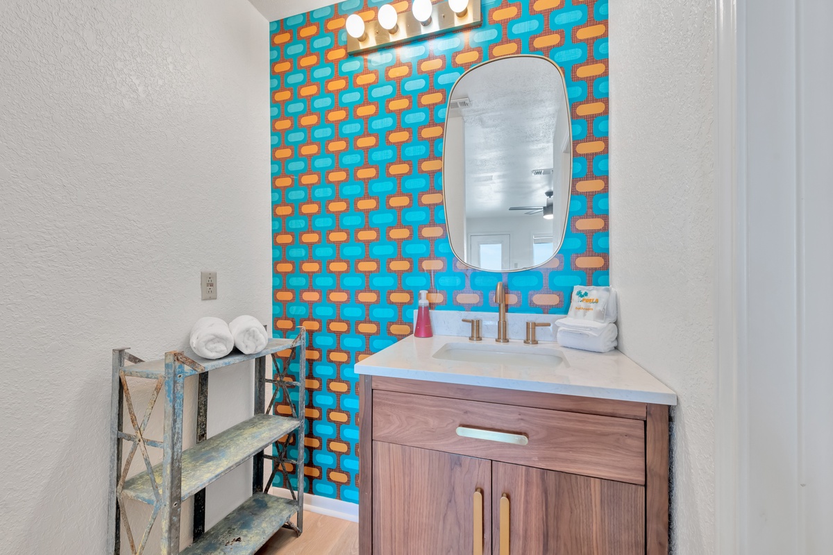 Your stylish powder room features vibrant wallpaper, a sleek vanity, and thoughtful touches like fresh towels and toiletries waiting for you.