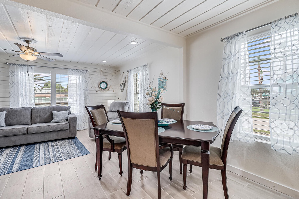 Your bright open living space combines elegant dining with cozy lounging beneath charming white wood beams and nautical touches.