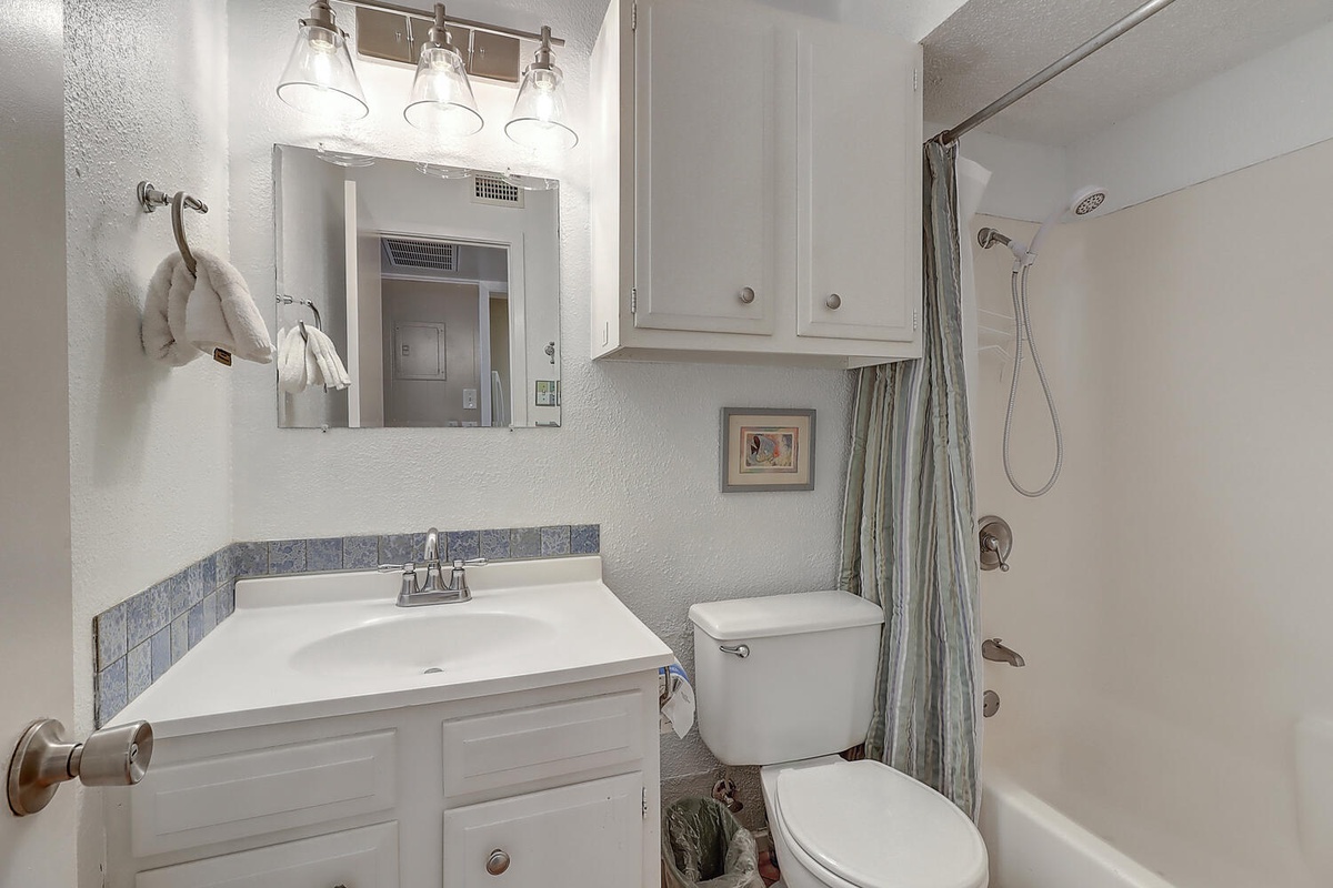 Step into your refreshing private bathroom featuring stylish lighting, fresh towels, and a spacious shower-tub combo for your comfort.