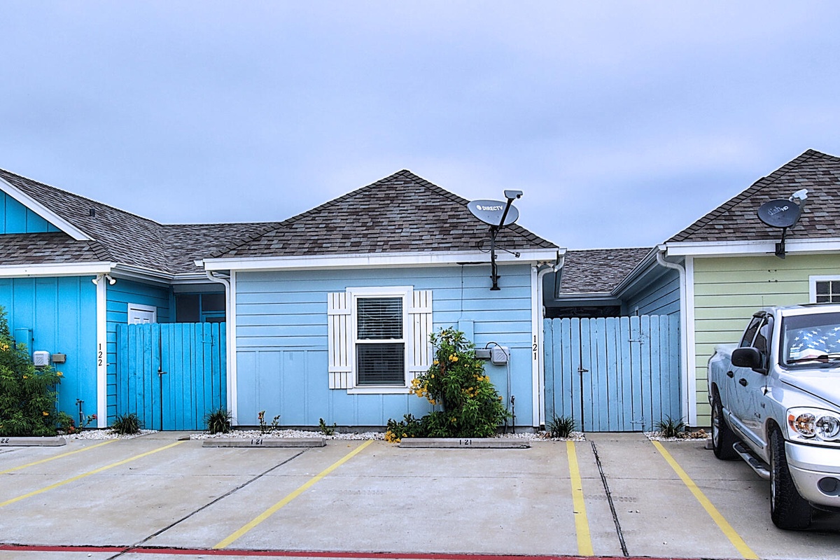 Charming beach cottage-style units with vibrant blue siding and convenient parking spaces for easy arrival.