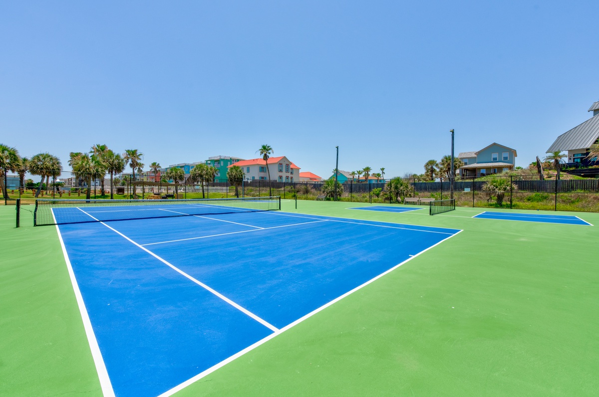 Challenge friends to a game on this pristine tennis court with tropical palm trees and colorful coastal homes as your backdrop.