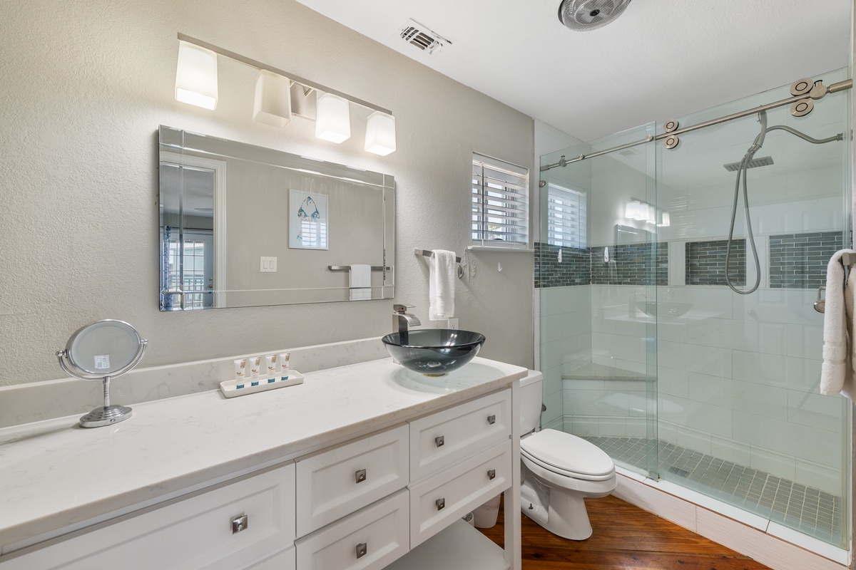 Refresh in your spa-inspired bathroom with a spacious walk-in shower, modern glass door, and sleek vessel sink. Soft lighting and coastal tones help you unwind after exploring.