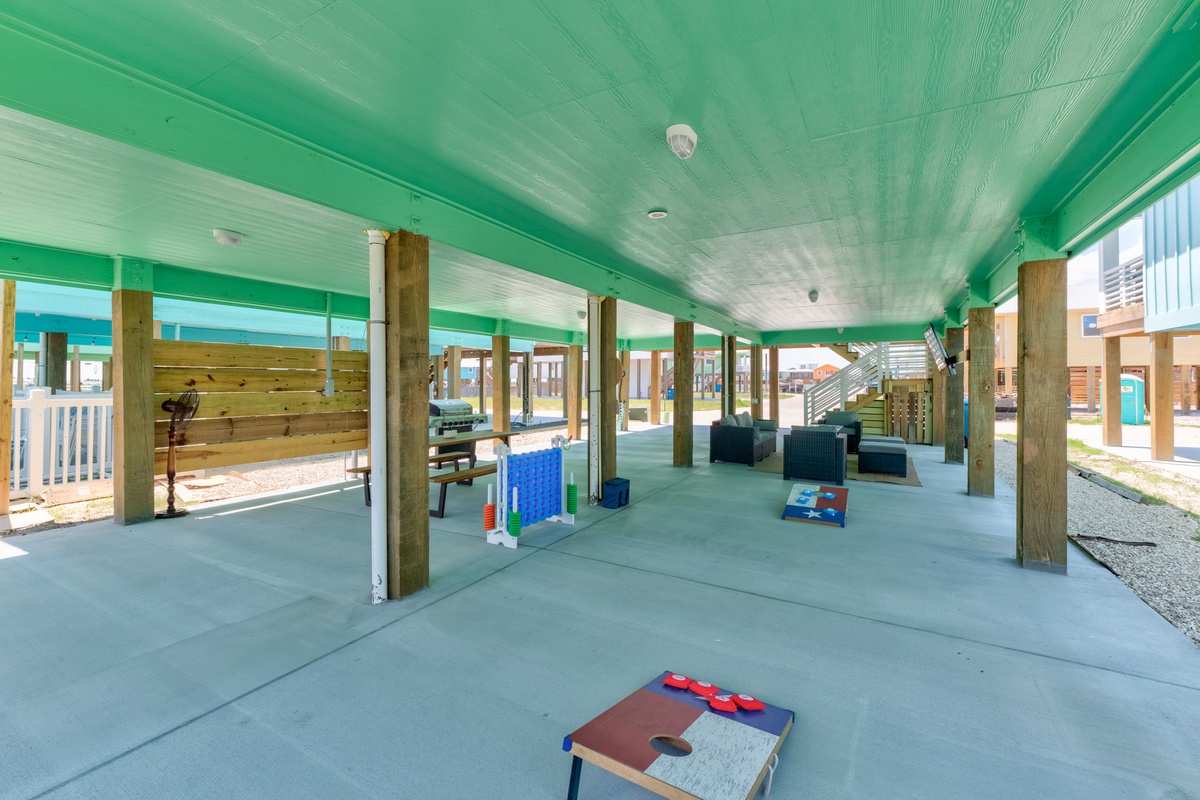 Your covered outdoor game area awaits with cornhole and seating, perfect for family fun while staying cool in the shade.