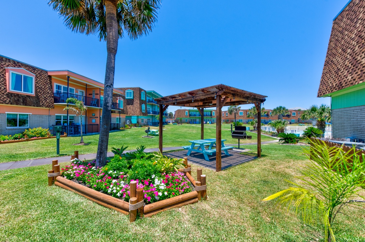 Colorful property buildings surround well-maintained grounds with tropical landscaping and covered outdoor seating areas.