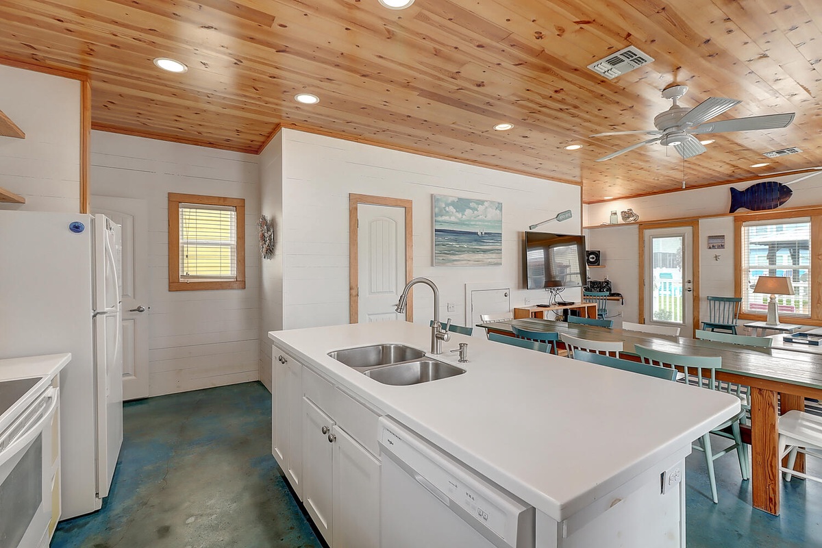 You'll love cooking in this bright coastal kitchen with gleaming white counters, modern appliances, and warm wood ceiling details.